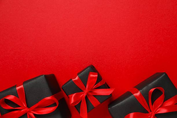 istock Festive gift box tied with bow on red background 2249610245