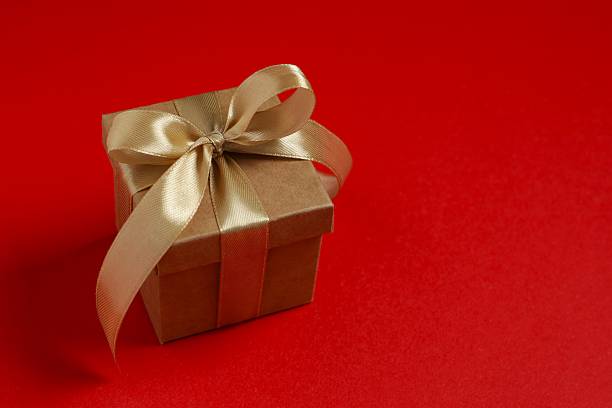 Elegant small red and gold present box with decorative ribbon, ideal for Christmas, New Year, or romantic celebration visuals.