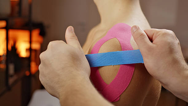 istock Person Applying Blue Tape on Pink Athletic Tape in Therapeutical Setting 2249614122