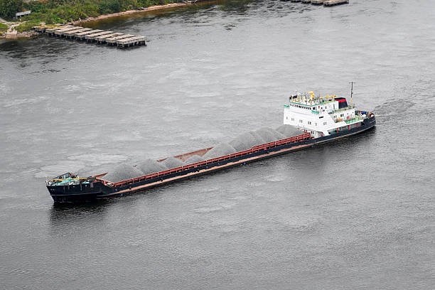 istock A cargo ship is seen transporting a significant load of materials along a river. The vessel moves quietly through the calm waters, surrounded by greenery and a distant dock 2249615509