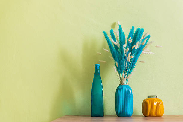 istock Orange and blue vases with blue and white decorative fluffy flowers on the table. 2249615872