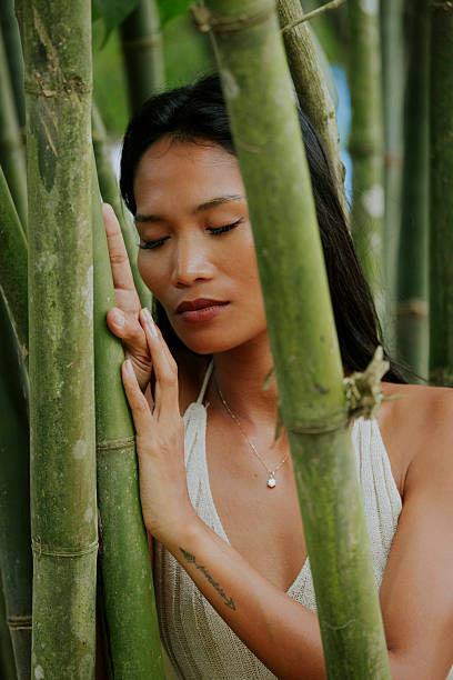 istock Woman surrounded by bamboo looking softly into the distance 2249617242