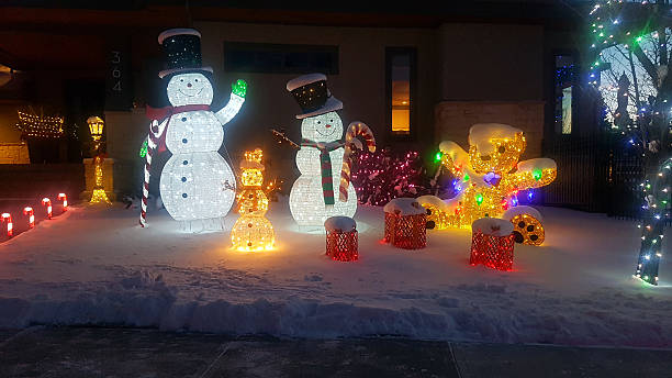 Calgary, Alberta, Canada- November 30, 2025:  Winter evening with snow. Front Yard of home decorated with lights and seasonal characters.  Close up at sidewalk .