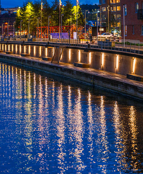 City waterfront illuminated by warm reflections on calm river at night.