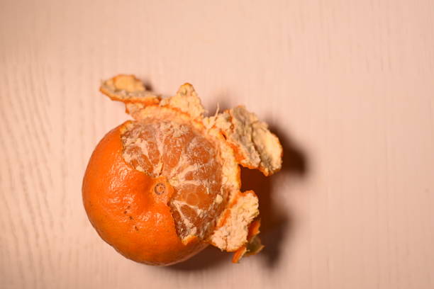 Top view of a half-peeled mandarin on a light background, empty space on the right for text or design.