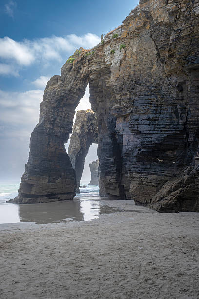 istock Rock arches and towering cliffs at As Catedrais Beach in Ribadeo, Spain, captured at low tide with soft light, ocean waves, and dramatic natural formations 2249630538