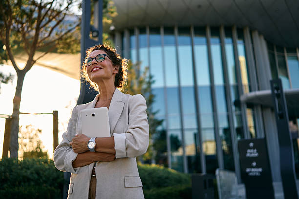 istock Businesswoman standing outdoors holding tablet looking away 2249631609