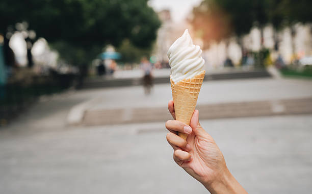 istock Soft serve ice cream cone held by hand in outdoor urban park setting with blurred background and warm sunlight glow 2249632858