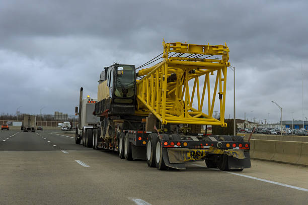Construction crane on flatbed truck drives along busy American highway