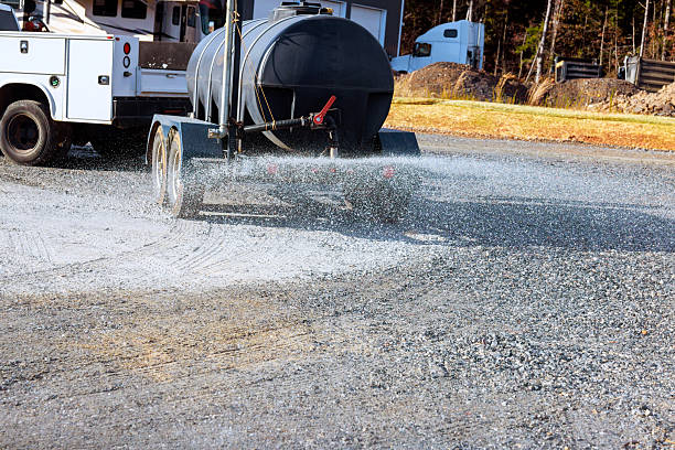 Huge mining machines with water tankers spraying transport routes for dust control
