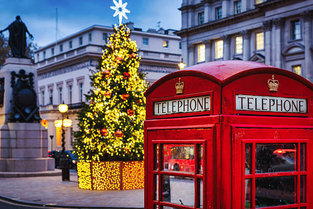 istock Christmas in London: a classic, red telephone booth in front of an illuminated Christmas Tree 2249635436