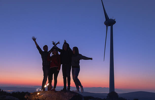 istock Group of Friends Posing with Open Arms at Wind Farm During Blue Hour, Emphasizing Friendship, Joy, and Sustainability 2249636204
