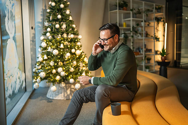 istock Man making phone call sitting by christmas tree in office 2249639045