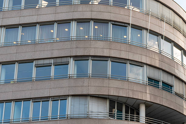 Modern curved office facade with large glass windows, metal railings and smooth horizontal lines of architecture