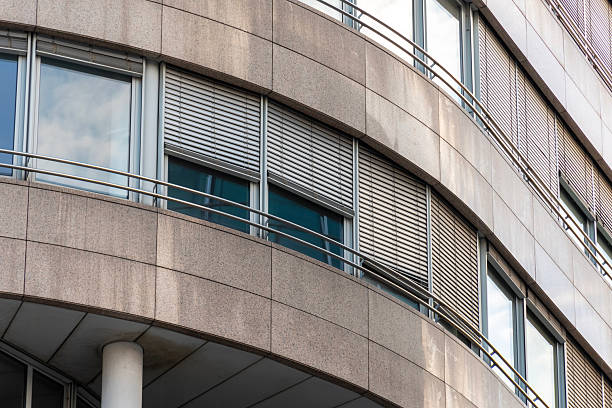 istock Curved facade of a modern office building with large windows, exterior shutters and stone cladding panels 2249644225