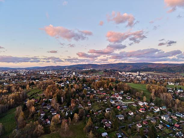 evening aerial view village under pastel sky with soft clouds, rooftops and winding streets, distant hills