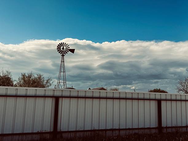 A single sustainable energy wind turbine has white fluffy clouds in the background on a blue sky.  Image is taken outside of Kenton Ohio in the Midwest.