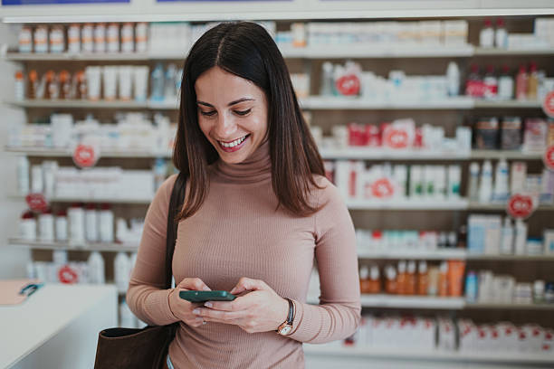 istock Young woman smiling while using smartphone in pharmacy 2249648275