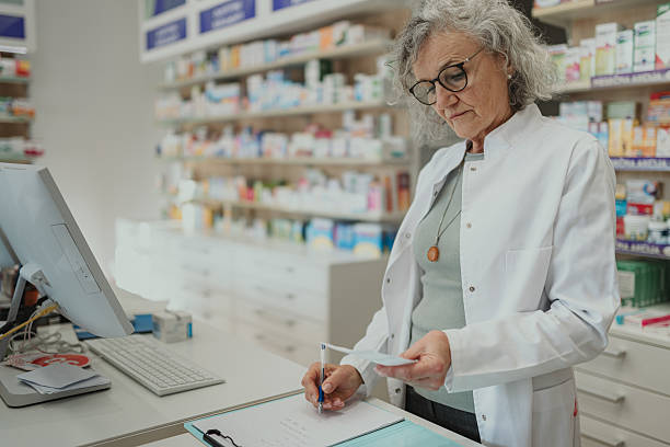 istock Senior pharmacist writing prescription in modern pharmacy 2249648870