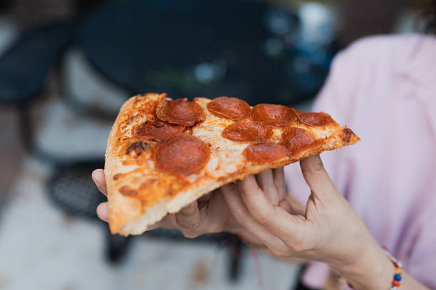 istock Person holding pepperoni pizza slice for lunch 2249650215