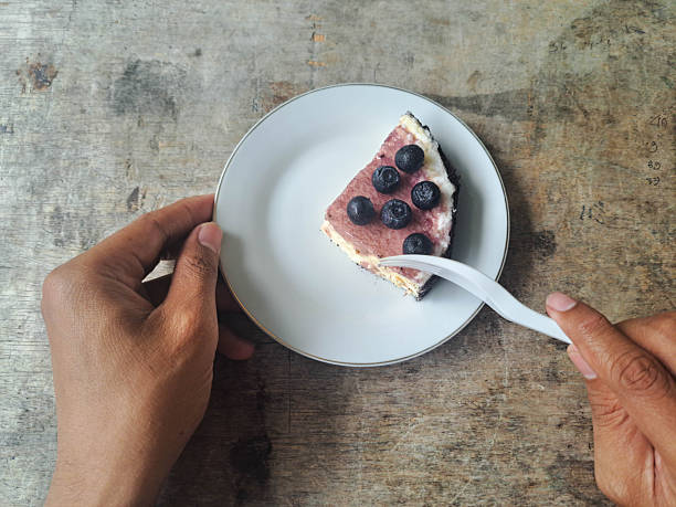 Young man eating Blueberry Cheesecake at meal times using a fork. Top View.