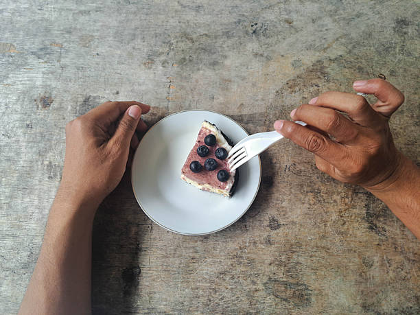 Young man eating Blueberry Cheesecake at meal times using a spoon in a restaurant. Top View.