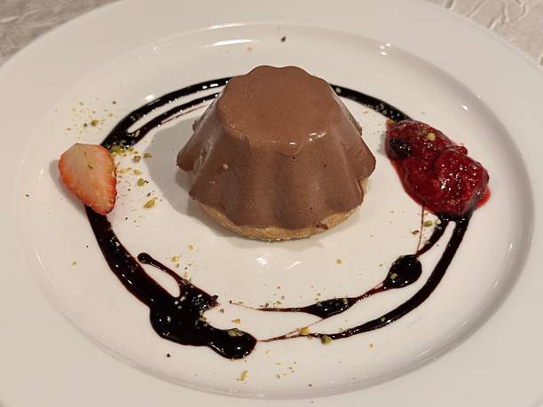 chocolate dome mousse cake, served on a cookie or shortcrust base and is garnished with fruit and a chocolate sauce.