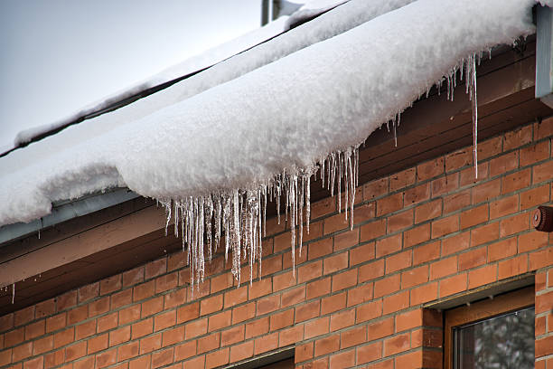 istock Icicles hanging from a snow-covered roof against a brick wall in winter 2249675467