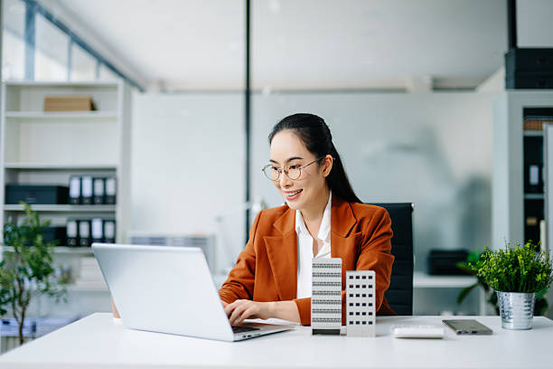 istock Mature real estate agent worker working with laptop and tablet at table in office and small house beside it. 2249676849