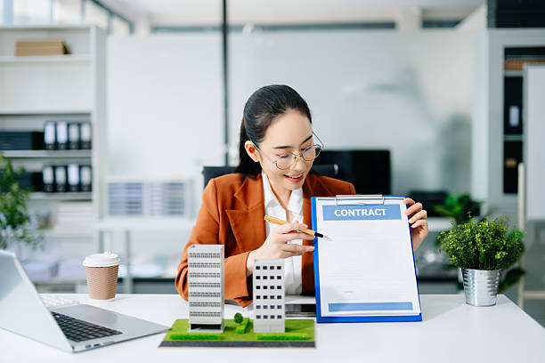 istock Mature real estate agent worker working with laptop and tablet at table in office and small house beside it. 2249676858
