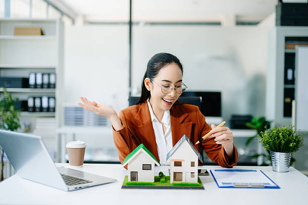 istock Mature real estate agent worker working with laptop and tablet at table in office and small house beside it. 2249676953