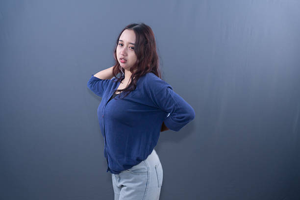 istock A pouting woman in a blue top poses with her hands behind her head and back 2249677865