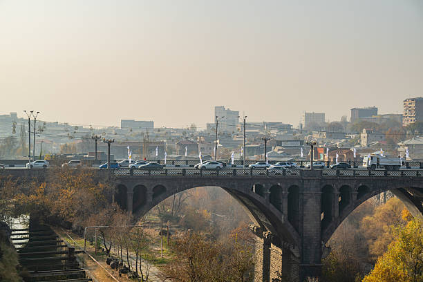 Yerevan Armenia 10.25.2025. A bridge Pobeda over a river with a city in the background. The bridge is busy with cars and trucks