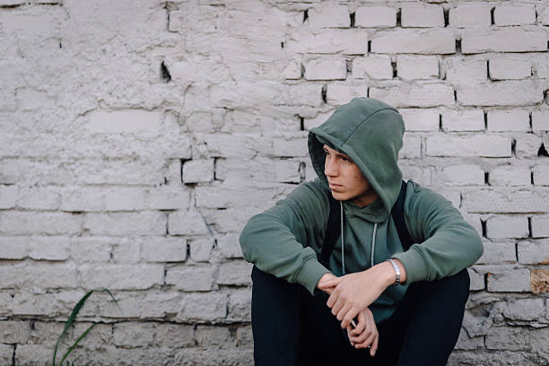 istock Young man feeling sad and lonely against brick wall 2249680768