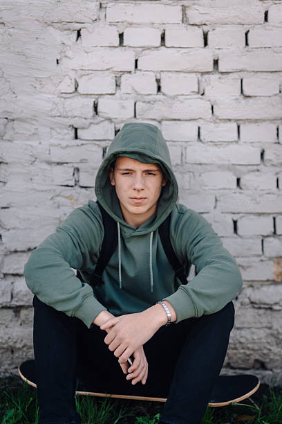 istock Teenager boy sitting on skateboard looking serious 2249681168