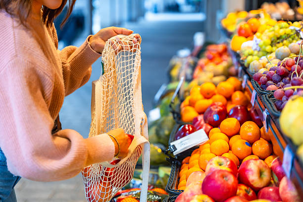 Woman shopping fresh organic fruit using reusable bag