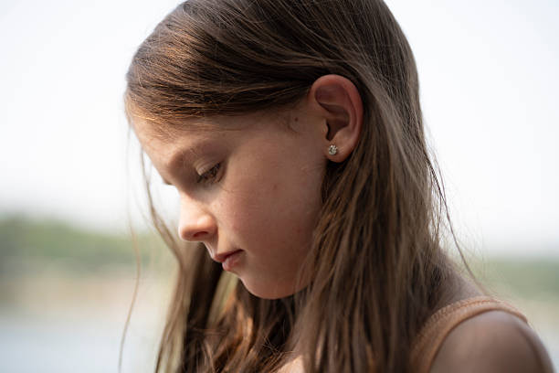 istock Cute long-haired girl side view close up looking down with sad expression, selective focus emotional childhood portrait with copy space 2249686343