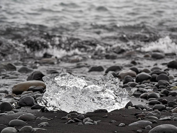 block of ice on black and volcanic sand