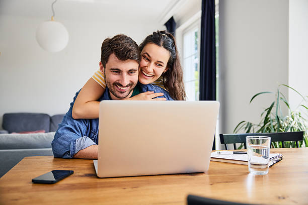 istock Young couple hugging while shopping online using laptop at home 2249691704