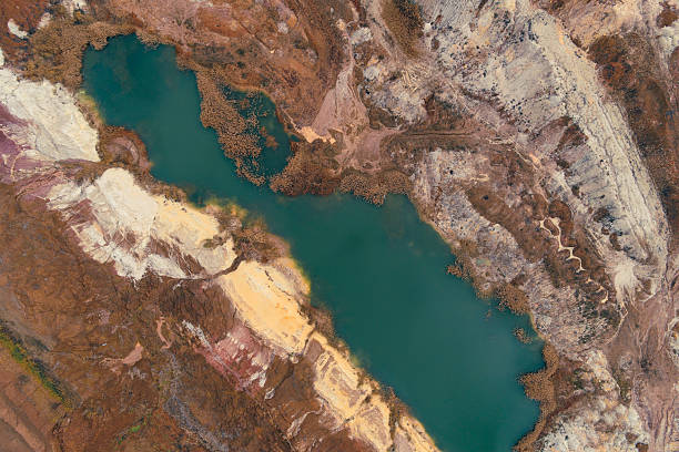 istock Top-down aerial view of a flooded open-pit mine with deep teal water contrasting with stratified white and reddish-brown geological layers. 2249692946