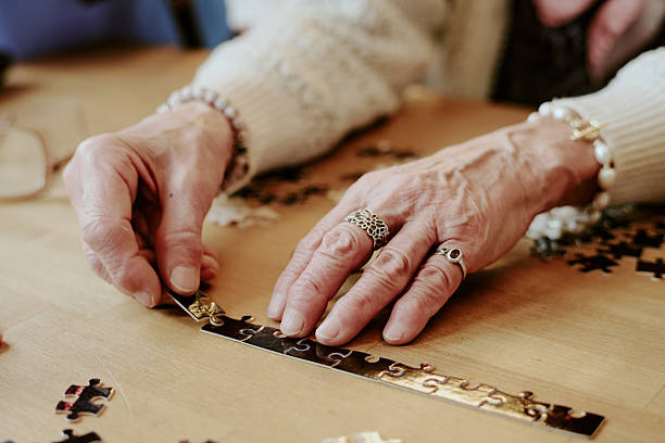 istock Senior Woman Assembling Puzzle Pieces on Wooden Table Indoors 2249695387