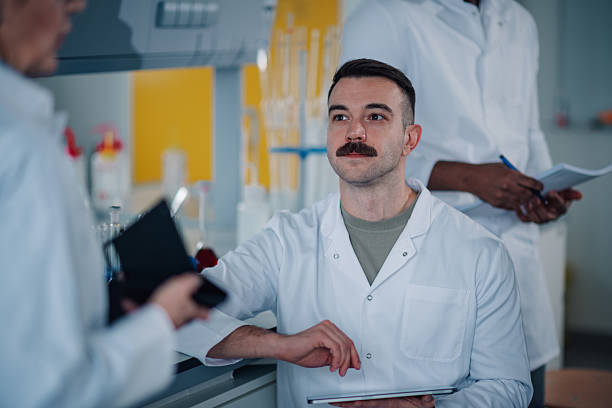 Scientists in lab coats collaborating, discussing research results and working together in a modern high-tech laboratory setting