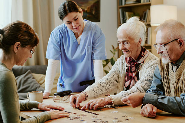 istock Senior Woman and Man Solving Puzzle with Nurse Assisting at Table 2249700966