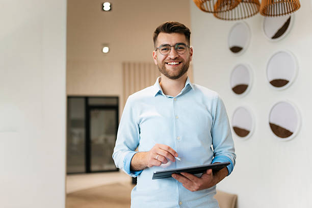 istock Confident businessman standing in modern office holding tablet 2249701273