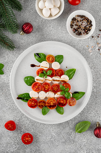 istock Festive Christmas Caprese salad with cherry tomatoes, mini mozzarella, and fresh basil served on a plate, styled in the shape of a Christmas tree for holiday celebrations. Top view. 2249701923