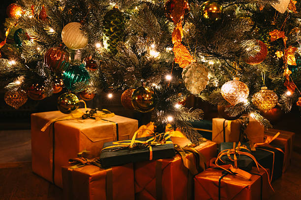 Wrapped gifts beneath glowing illuminated Christmas tree at night