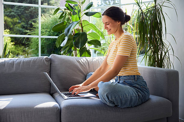 istock young woman using laptop at home sitting on sofa 2249707032