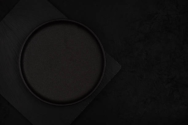 istock Top-view modern dark food mockup with an empty black plate on textured slate stone, offering clean copy space for menu design, restaurant branding, advertising visuals, and creative presentations 2249707591