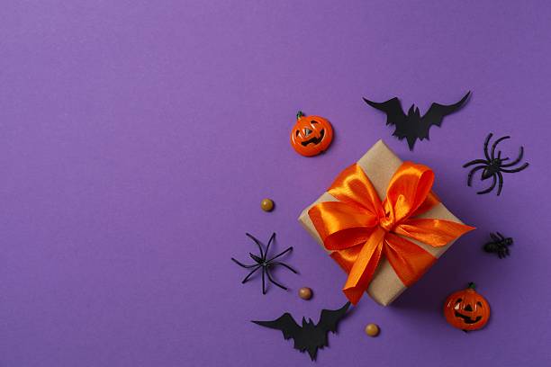 istock Halloween holiday decorations including gift box, pumpkins, spiders, bats on color background 2249708414