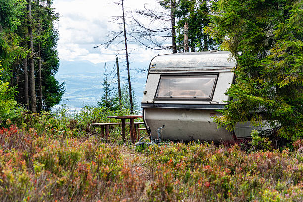 istock Secluded forest campground with weathered trailer, picnic table, and distant mountain view 2249709154